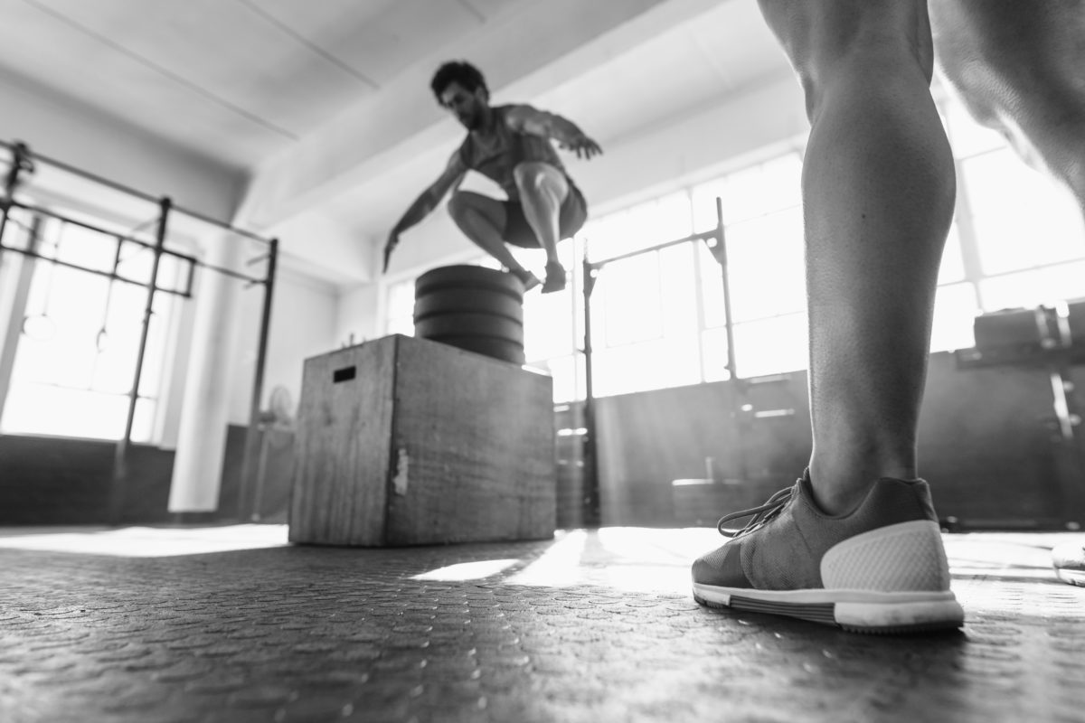 Fit man box jumping at cross training gym strong powerlifter bodybuilder deadlifting heavy weight with muscular back