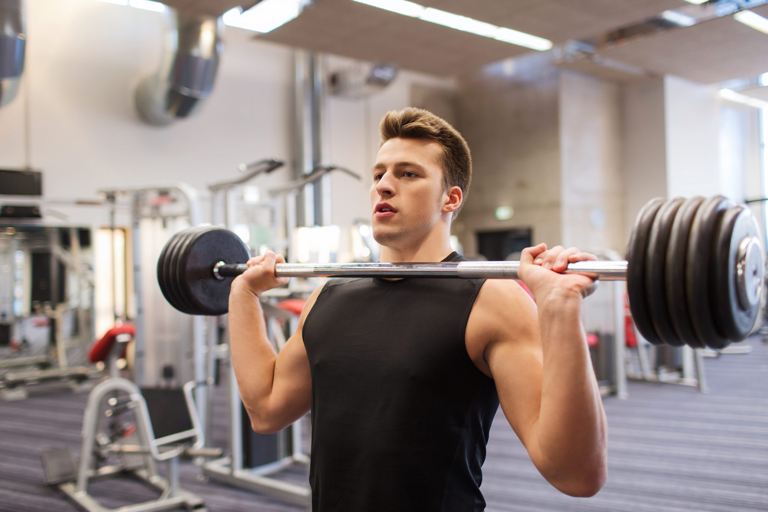 young man flexing muscles with barbell in gym header image