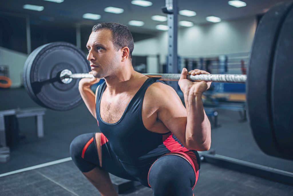 Powerlifter doing squats with barbell in gym