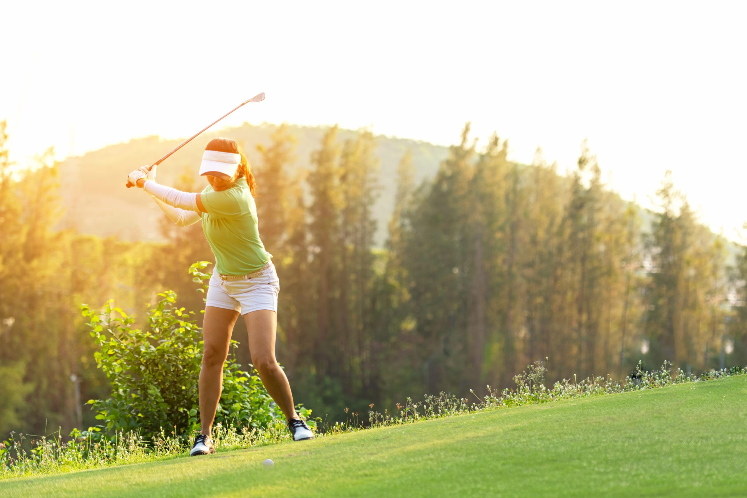 Sporty woman golfer player doing golf swing tee off on the
