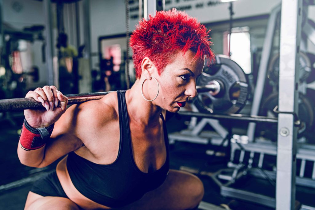 Close up on Olympic weightlifting woman training at the gym and performing a dead squat