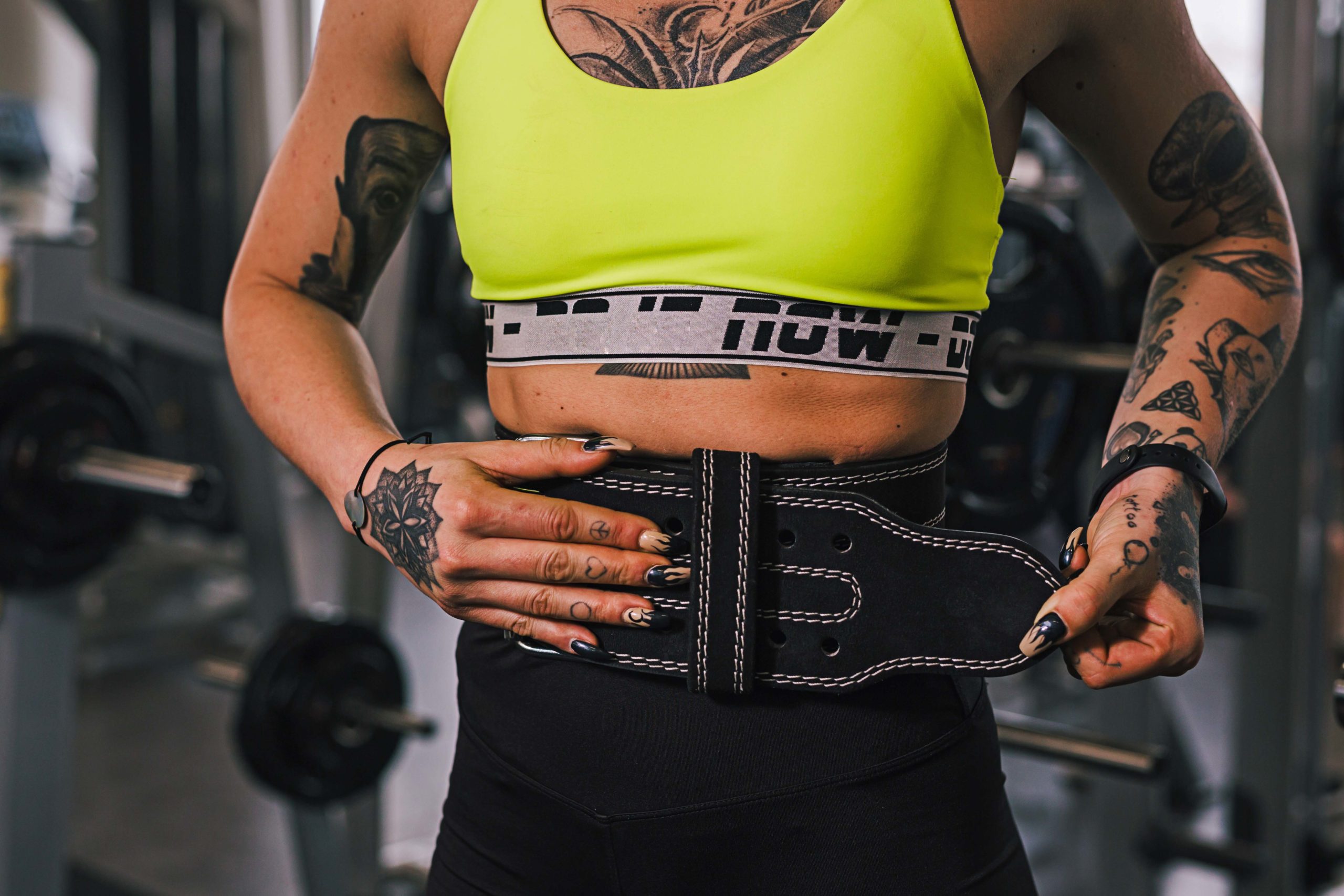 young woman workout in gym, putting belt for power lifting Strong, muscular man performing the kettlebell swing