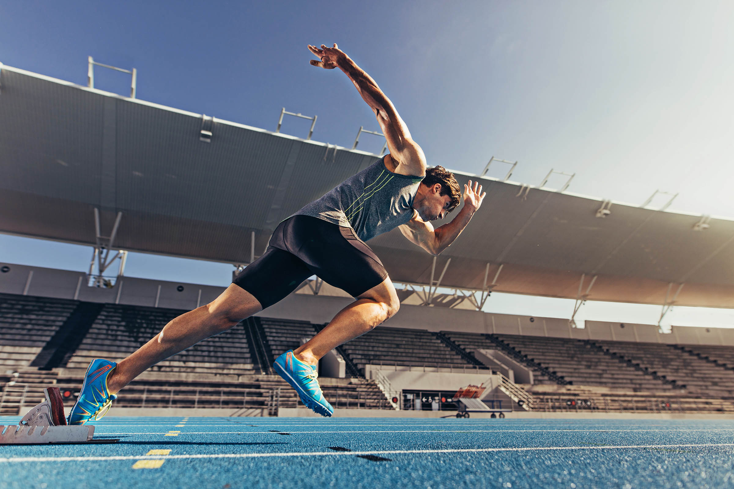 Sprinter taking off using starting blocks to start his run on running track in a stadium. Athlete starting his sprint on an all-weather running track.