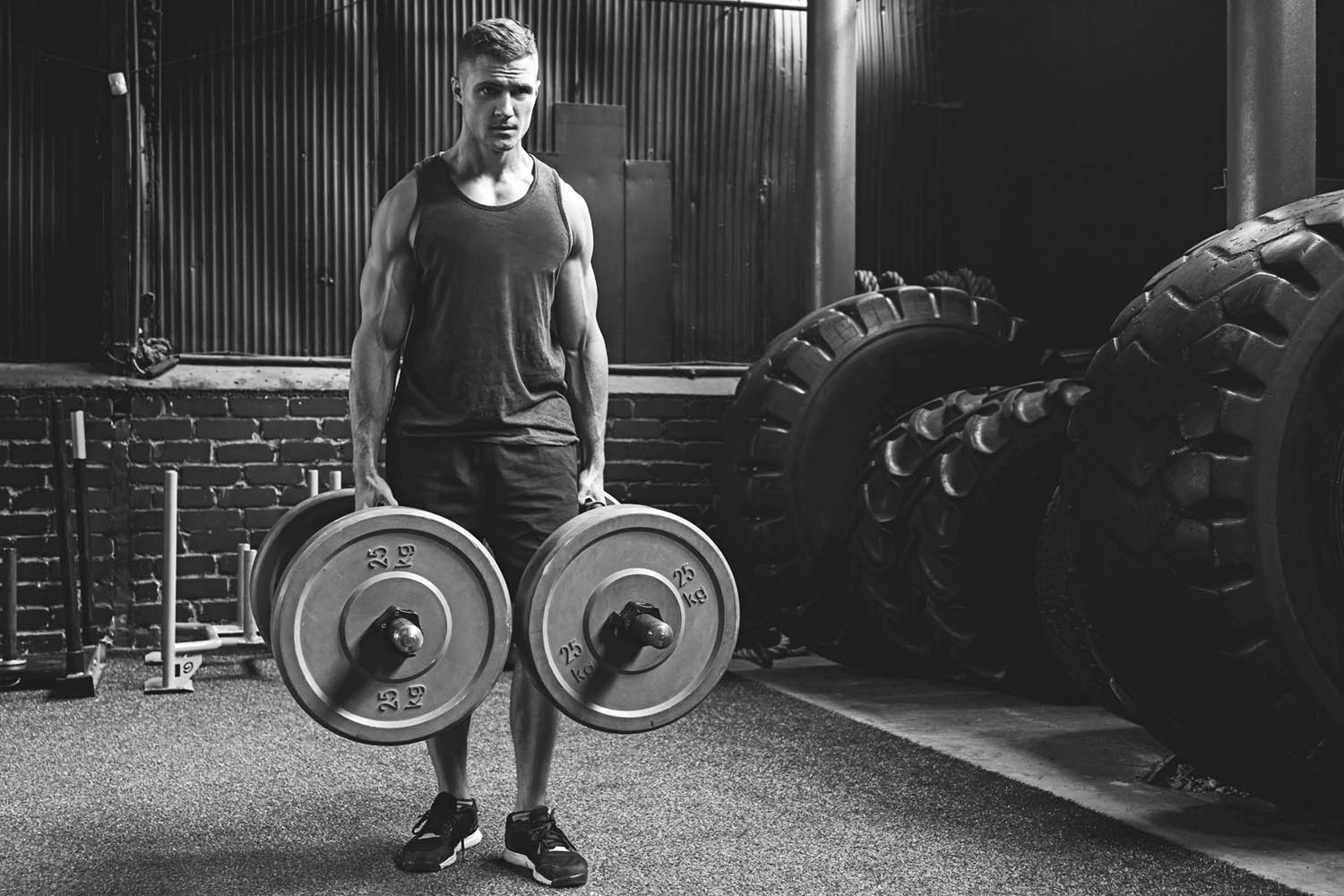 Young muscular sportsman doing farmer's walk exercise during his cross training workout