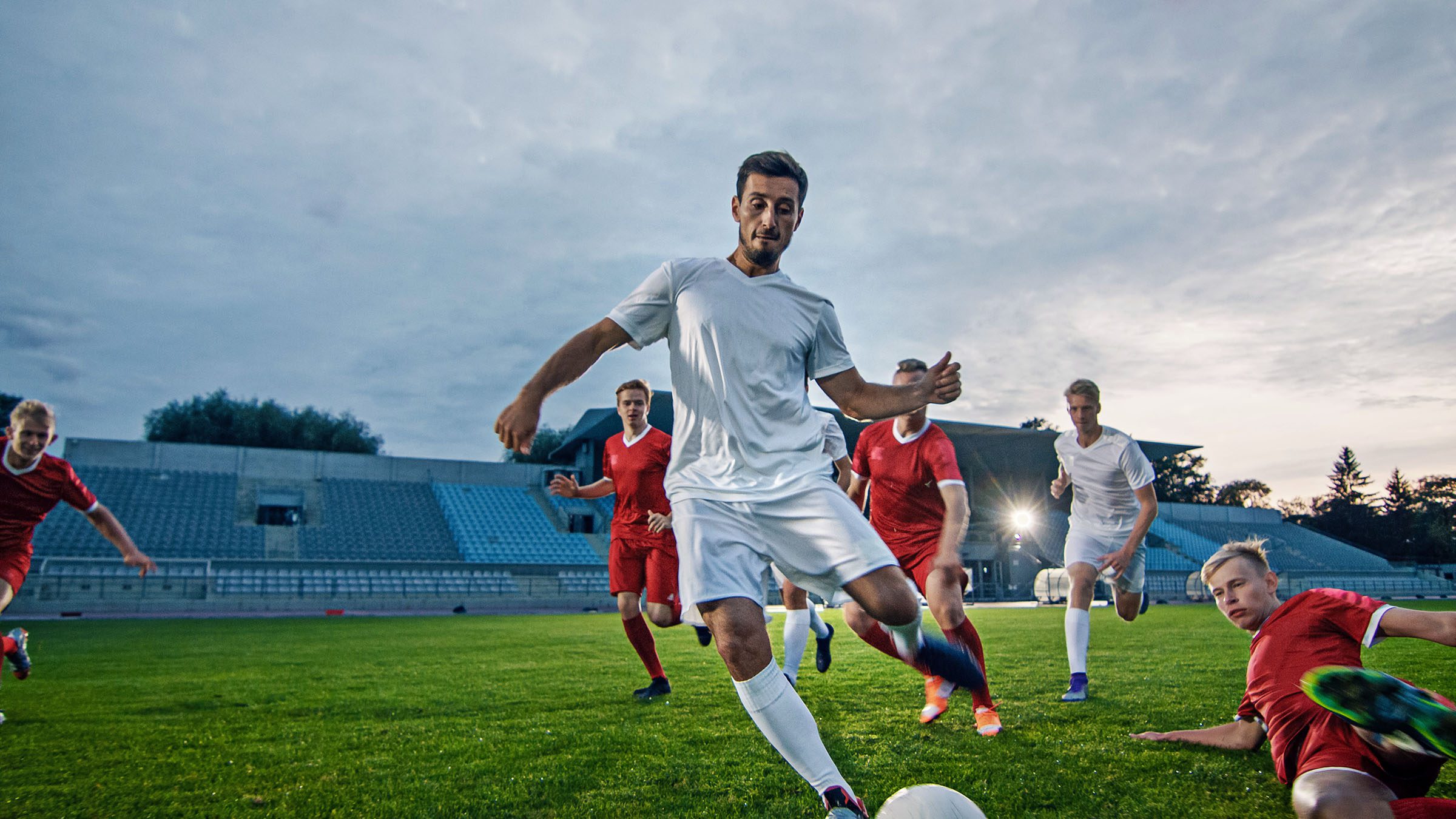 Professional Soccer Player Outruns Members of Opposing Team and Kicks Ball to Score Goal. Soccer Championship on a Stadium.