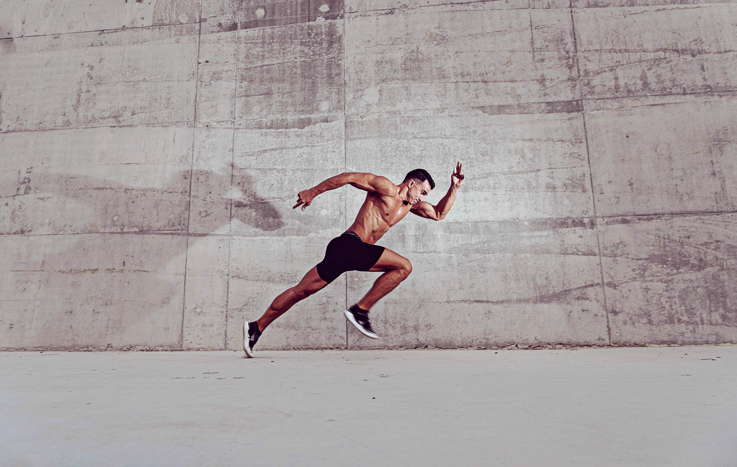 Muscular shirtless caucasian male athlete does an explosive sprinting start