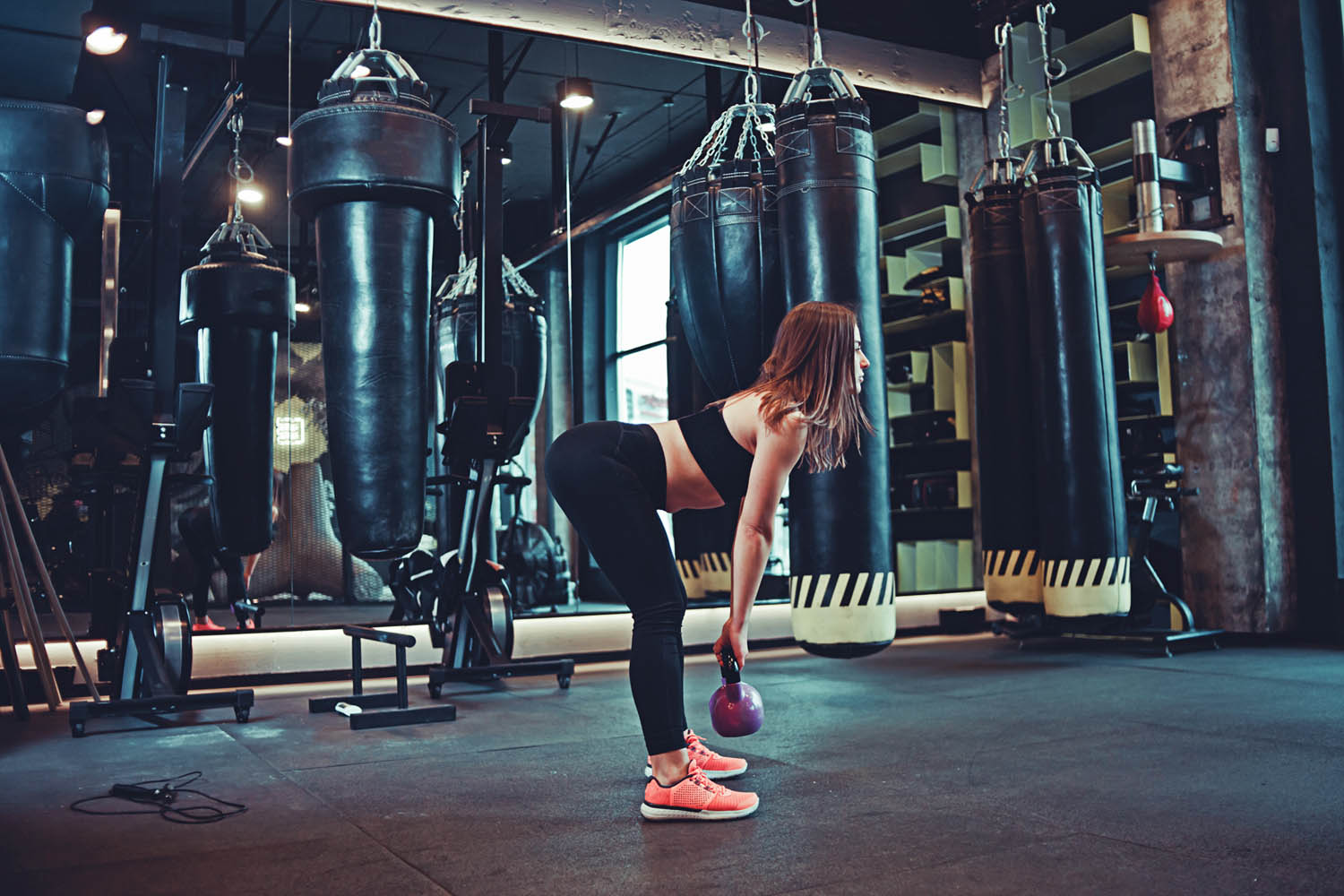 Woman doing Romanian deadlift exercise with kettlebell in gym.