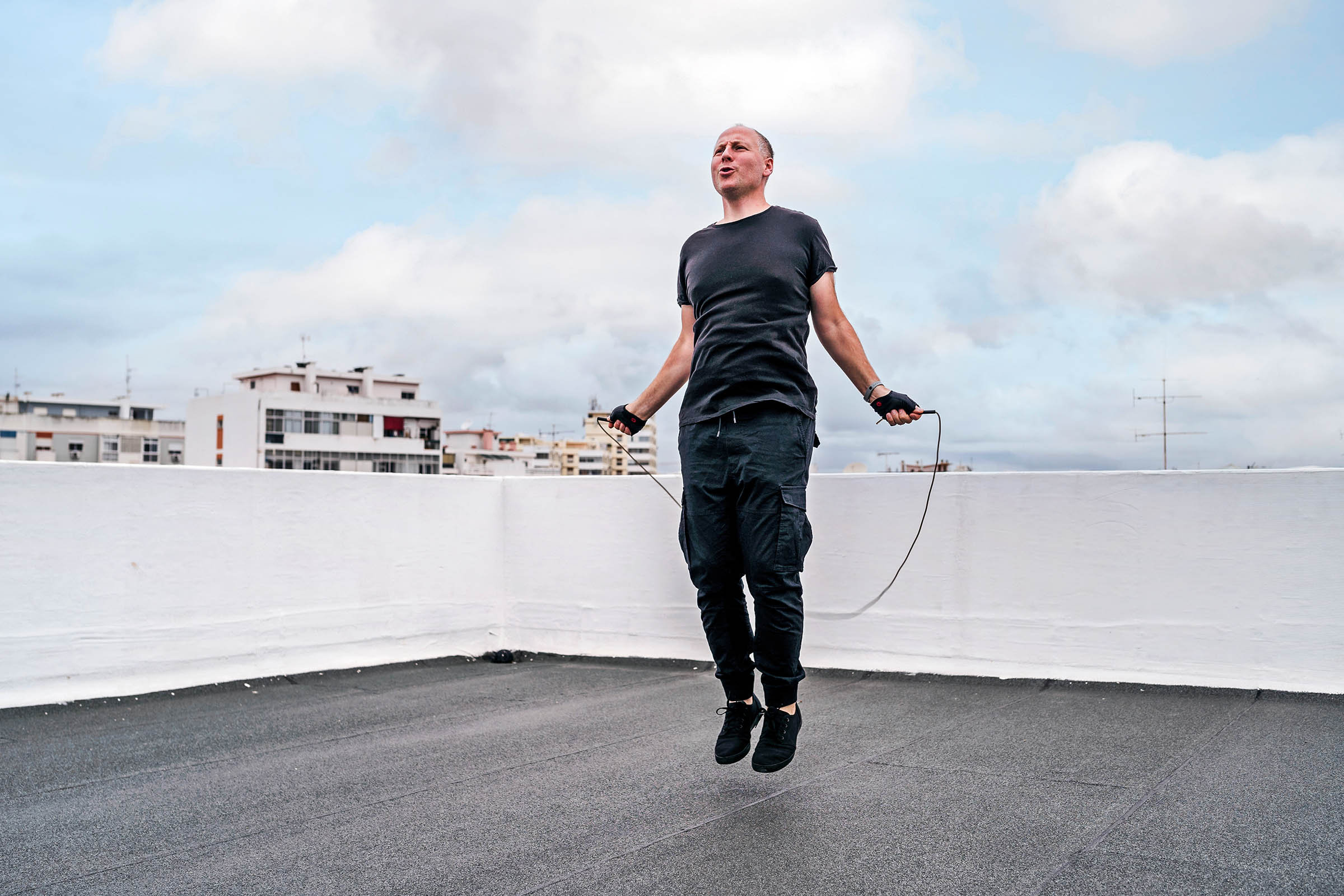 Man on a rooftop exercising with a jump rope