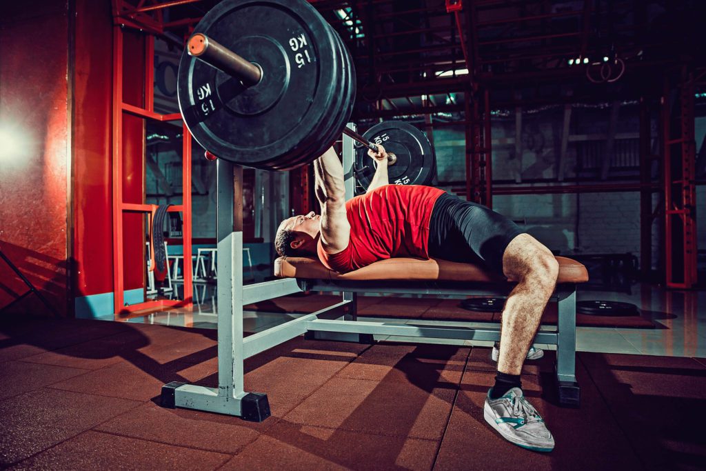 Man doing barbell bench press workout in gym after doing a bench press warm up