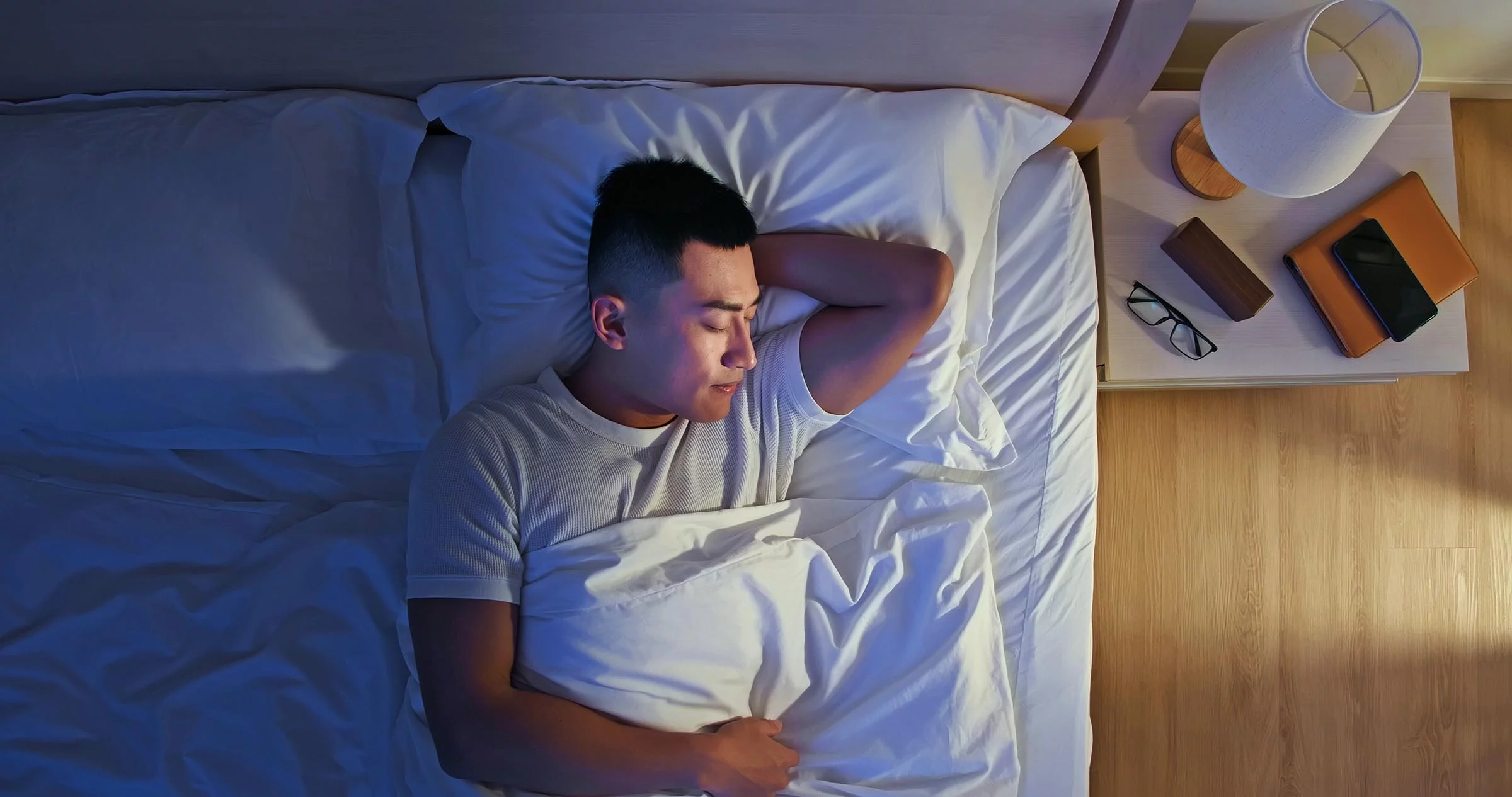 Overhead view of man sleeping well in a bed with smile at night.