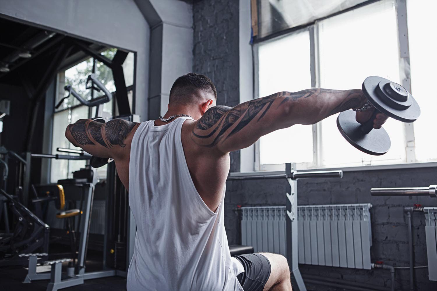 Rear view shot of a tattooed muscular bodybuilder doing lateral