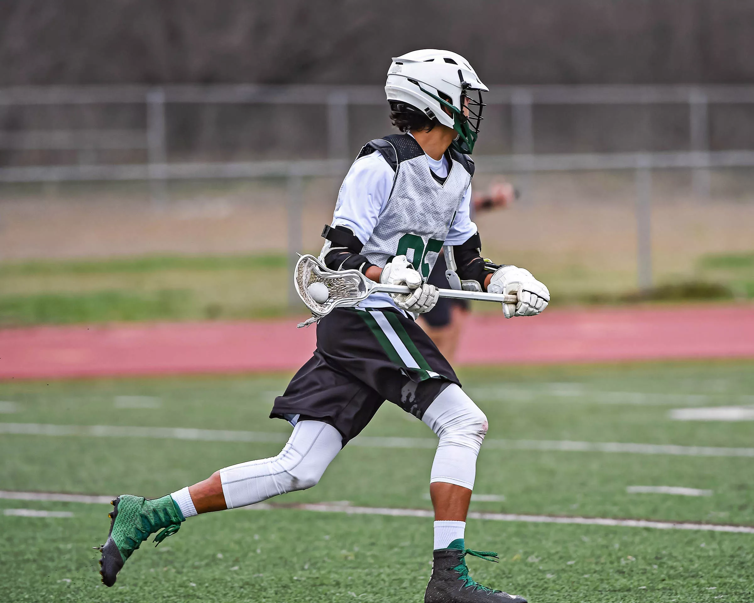 Athlete doing lacrosse exercise on field in full uniform