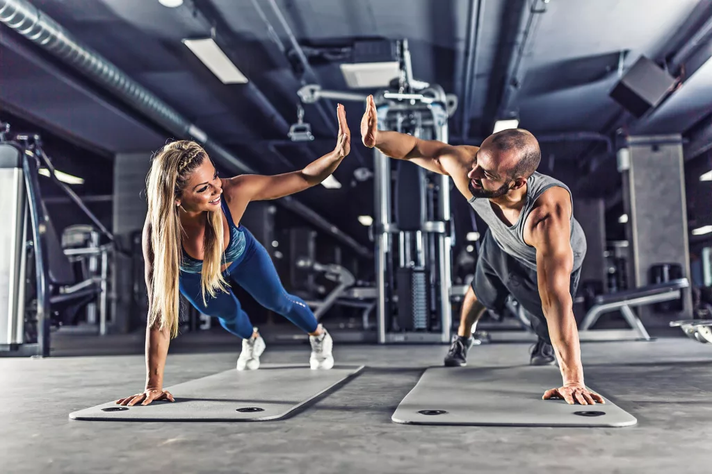 Sport couple doing plank exercise workout and giving each other high fives. Couple holding each other accountable to their fitness goals