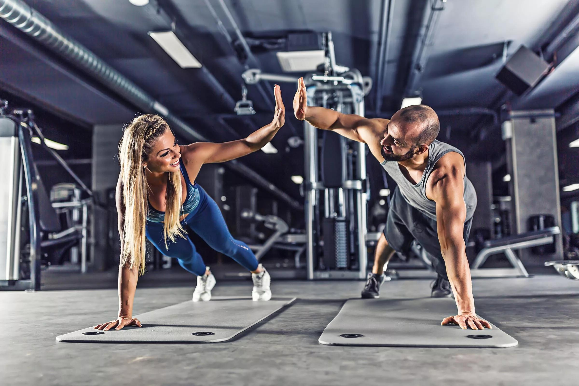 Stay Accountable and Crush Your Fitness Goals Sport couple doing plank exercise workout and giving each other high fives. Couple holding each other accountable to their fitness goals