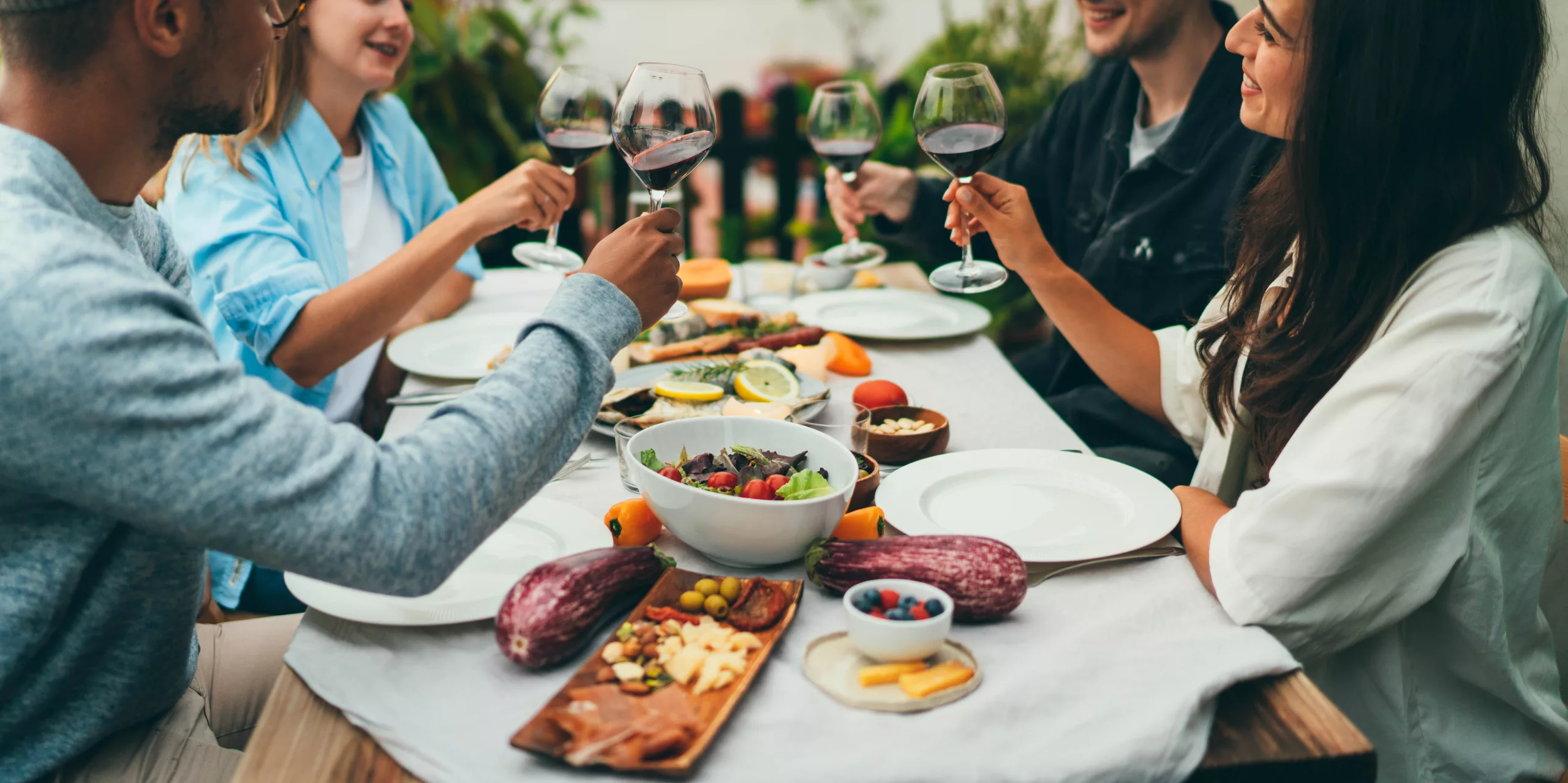 Group of people dining out smiling and laughing, Friends sitting at the dinner table practicing healthy eating habits while on vacation