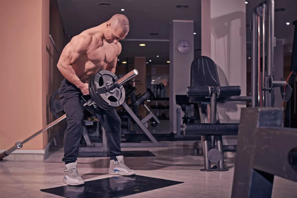 Body building in gym performing T-bar rows to build bigger back muscles