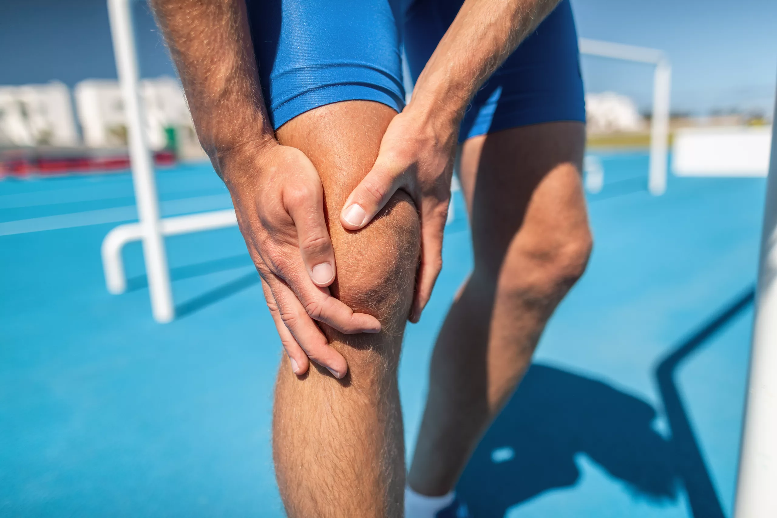 Knee pain professional athlete sport injury - sports running knee acciden on man runner. Sprained knee joint, arthritis. Closeup of legs, muscle and knee outdoors.
