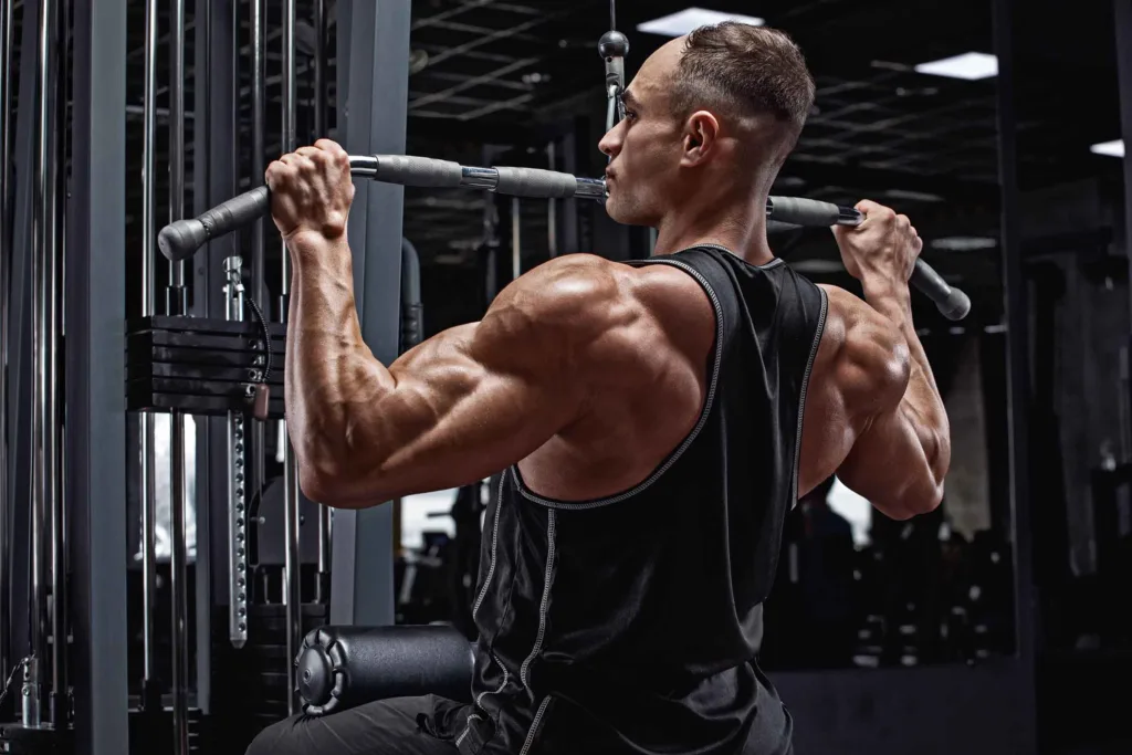 Strong man in gym facing backward on lat pulldown machine doing lat workout