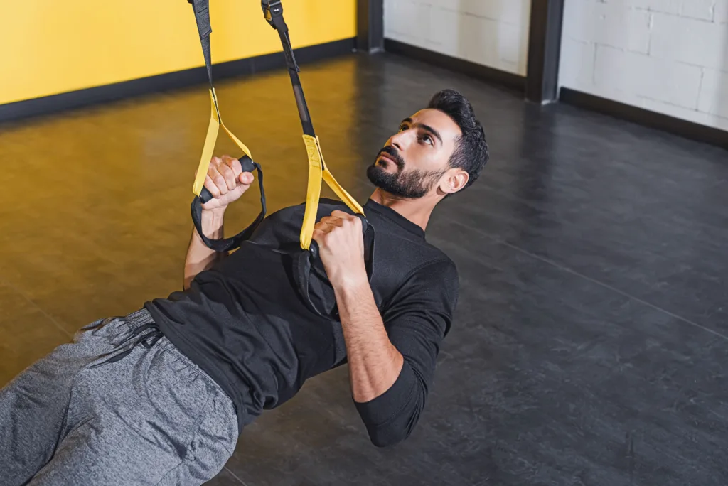 Muslim athlete in gym using TRX bands for workout during Ramadan