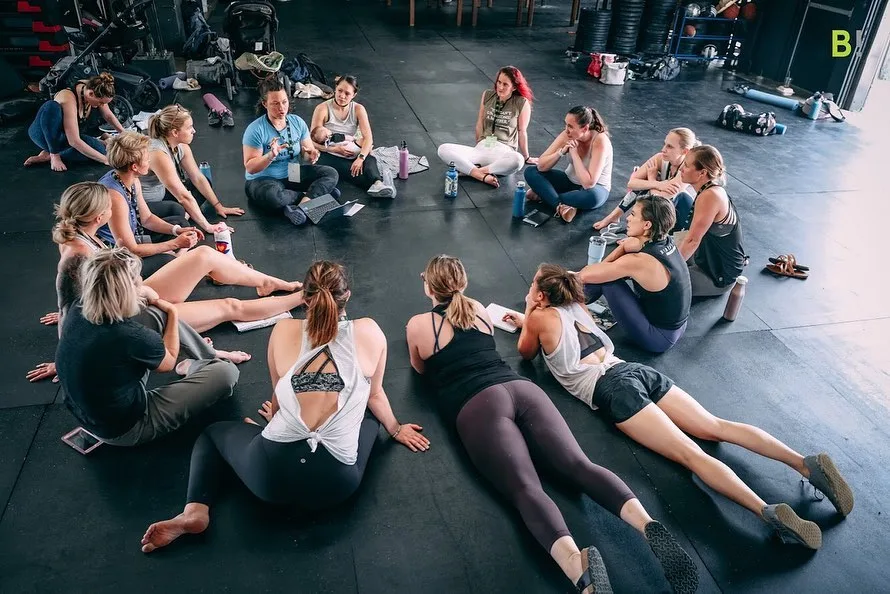 Women on the floor of a gym in workout gear