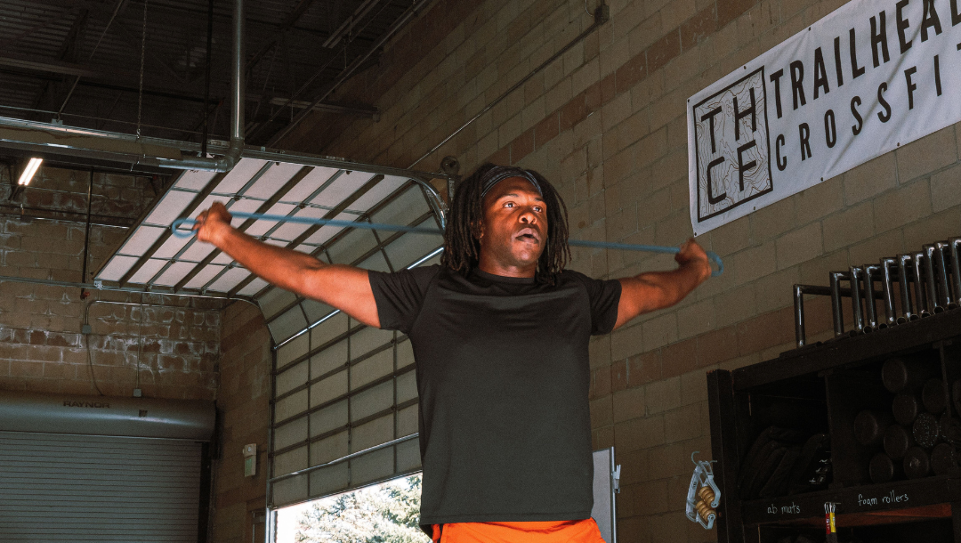 Male athlete warming up upper before before lifting with a band in gym