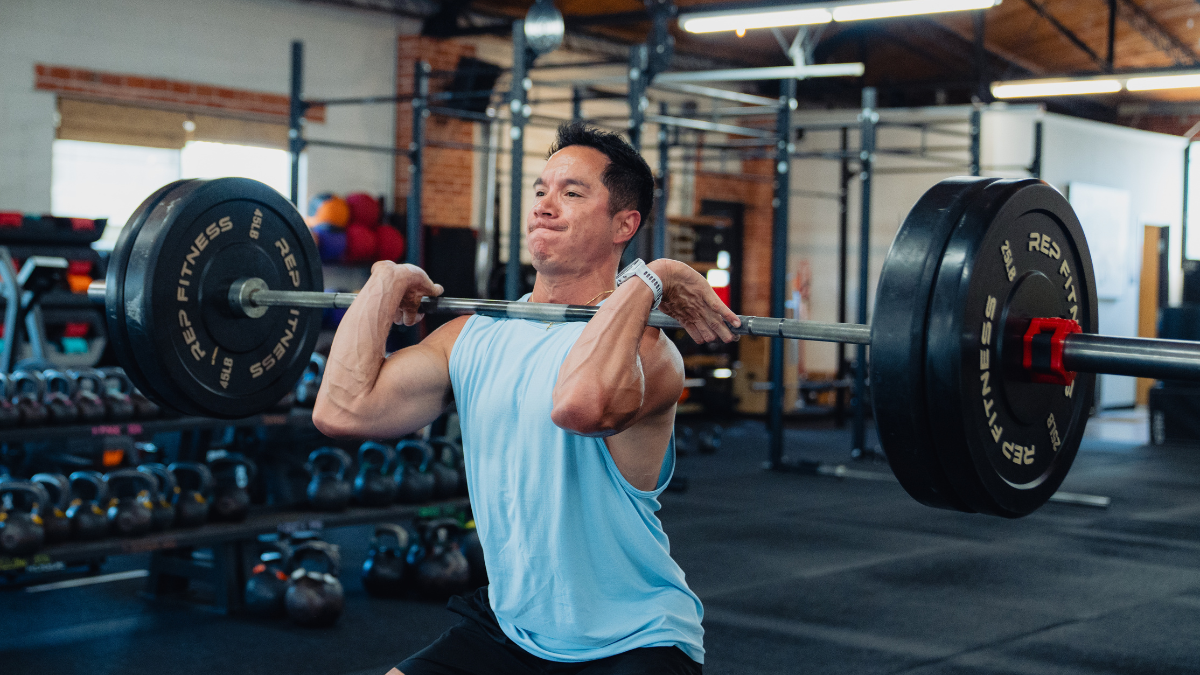 Man doing cleans in gym with barbell